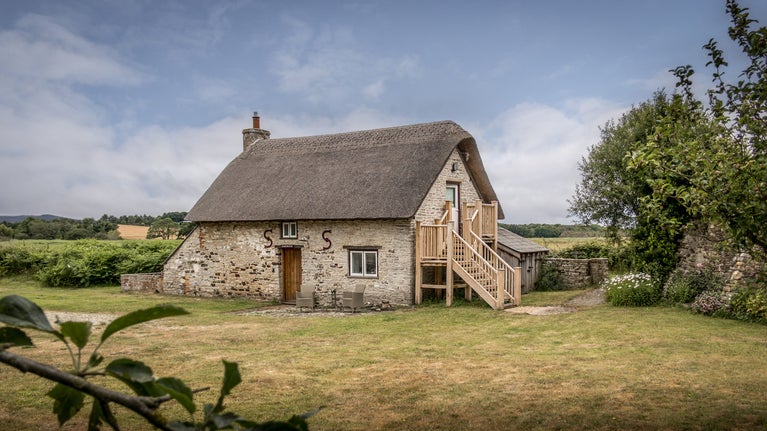 The exterior of The Bakehouse, a two-storey thatched cottage, Dorset